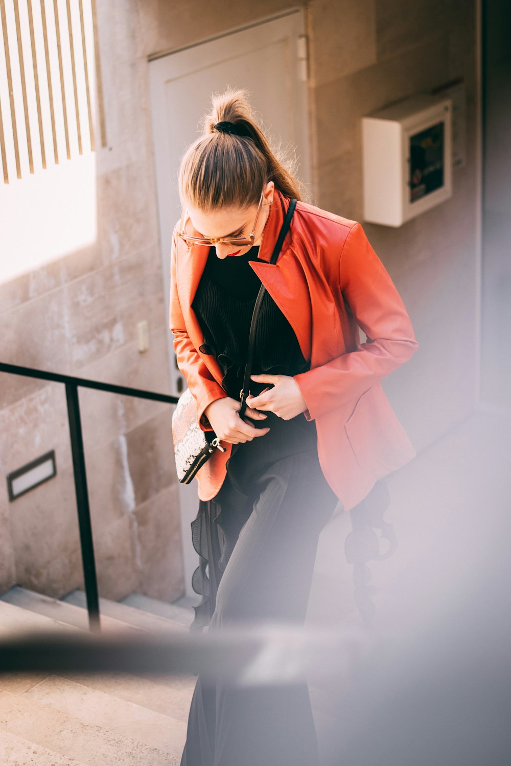 woman wearing orange jacket and black pants with black inner shirts