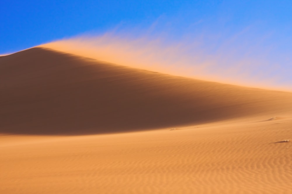 Una gran duna de arena con un cielo azul al fondo