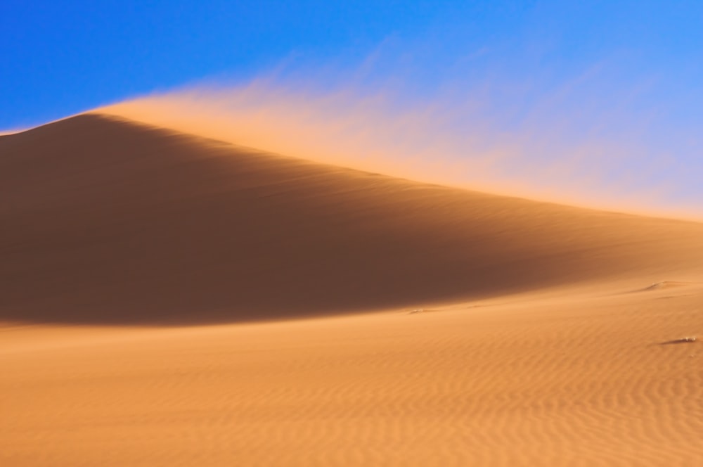 a large sand dune with a blue sky in the background