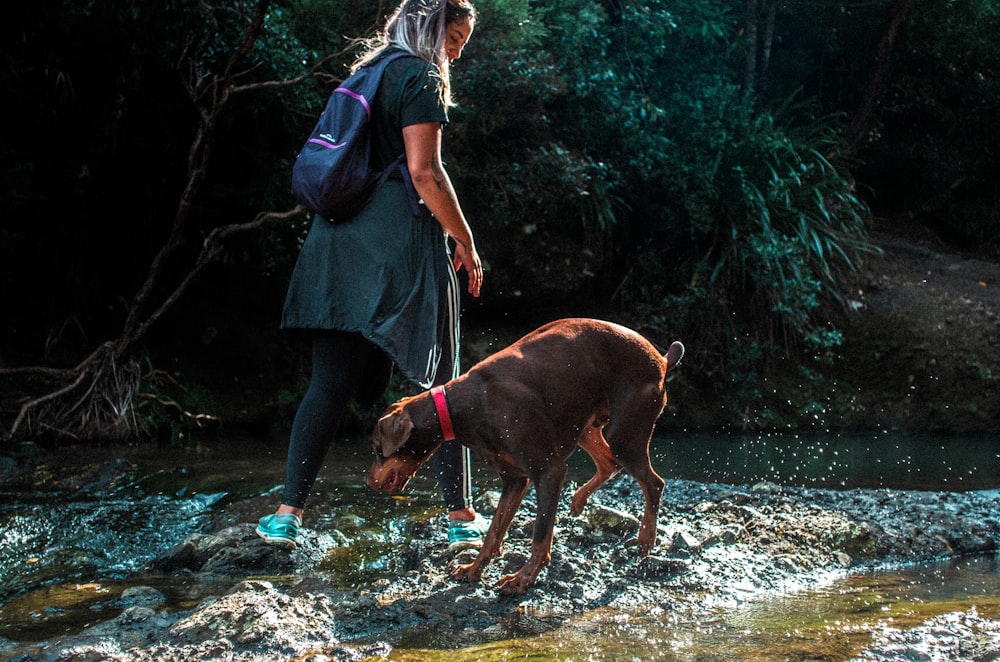 woman standing near dog in river