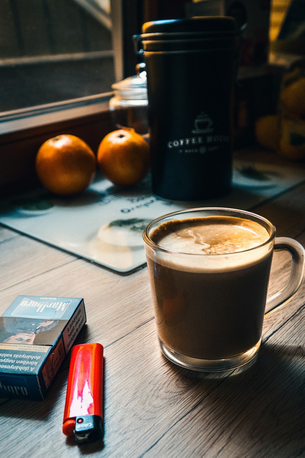 Tasse Kaffee neben Zigarettenschachtel und Feuerzeug