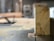 A piece of wood with visible tree rings is positioned upright on a table saw. Sawdust is scattered around, indicating recent cutting activity. The background shows a blurred interior of a workshop or carpentry setting.