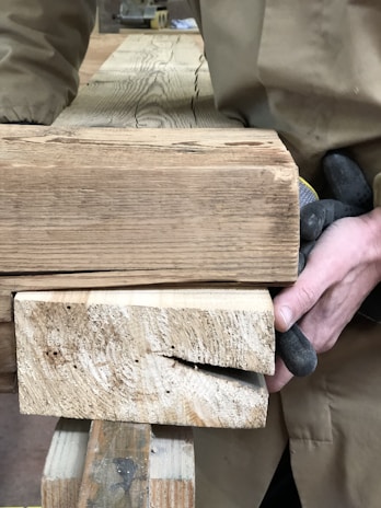 Smiling carpenter inspecting high-quality timber supplied by Timberhood on a construction site.