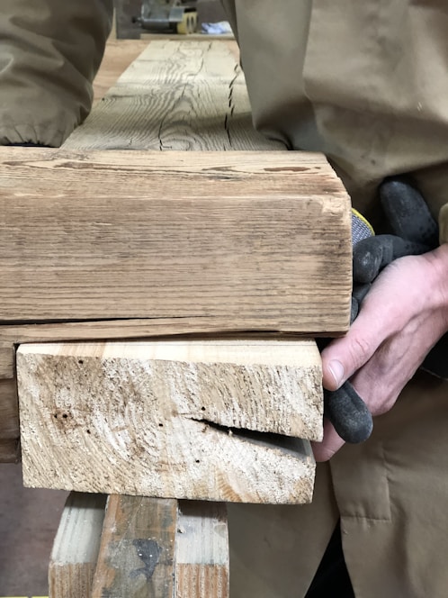 A professional worker handling sturdy wooden beams at a construction site, highlighting natural wood textures.