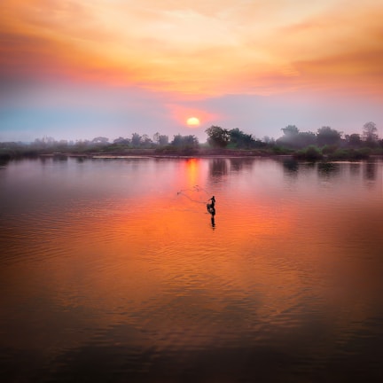 A fisherman casting his line into the lush, tropical waters of Río San Carlos at sunrise.