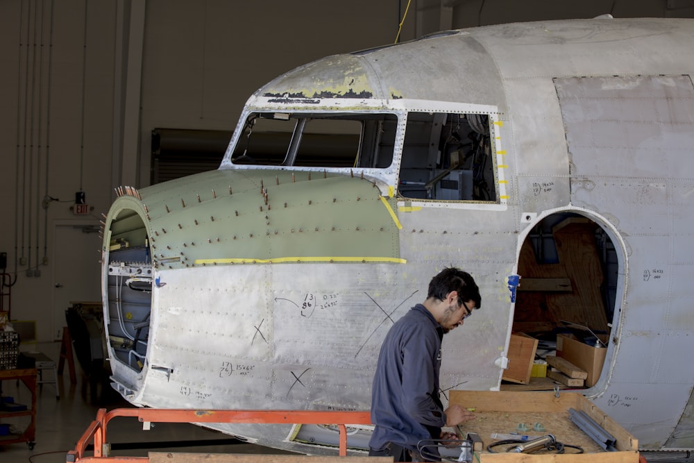 man standing beside gray plane