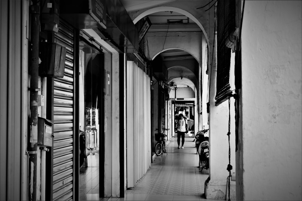 grayscale photography of person walking inside building