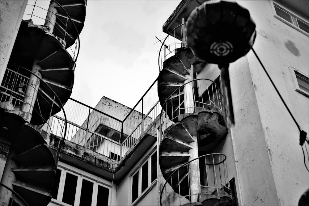 Graustufenfotografie der Wendeltreppe neben dem Gebäude