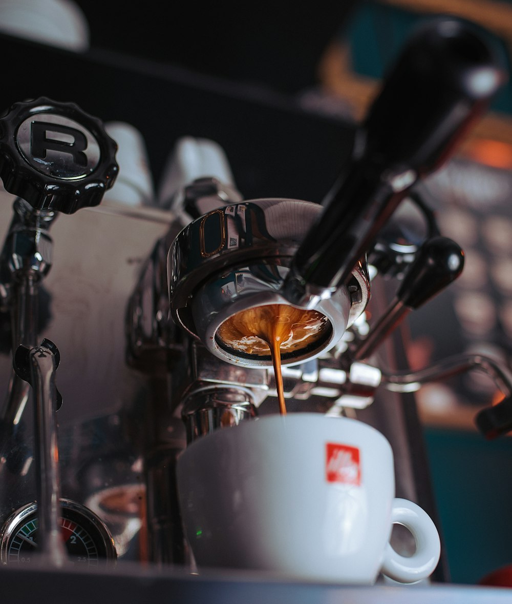 Tasse à thé en céramique blanche sur machine à expresso en acier inoxydable gris