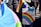 A person holds a rainbow flag and a colorful protest sign that reads 'Some parents are their child's first bully... GSA's save lives!' The background shows other people, some wearing jackets.