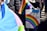 A person holds a rainbow flag and a colorful protest sign that reads 'Some parents are their child's first bully... GSA's save lives!' The background shows other people, some wearing jackets.
