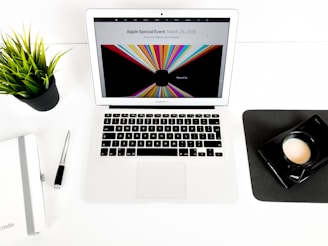 A friendly technician working carefully on a MacBook in a bright, organized workspace.