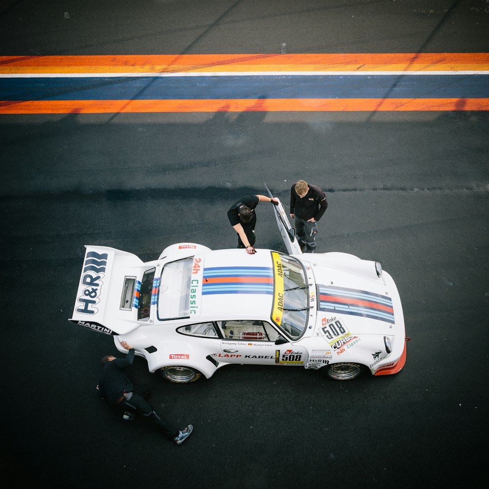 classic white Porsche 911 at pit stop with crew