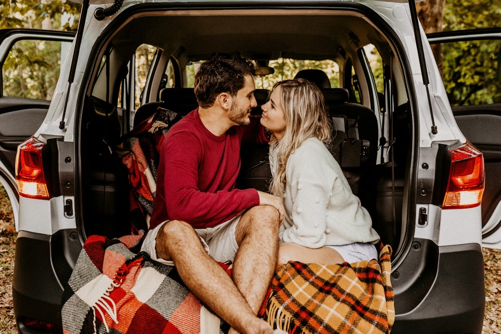 homme et femme assis sur le coffre de la voiture