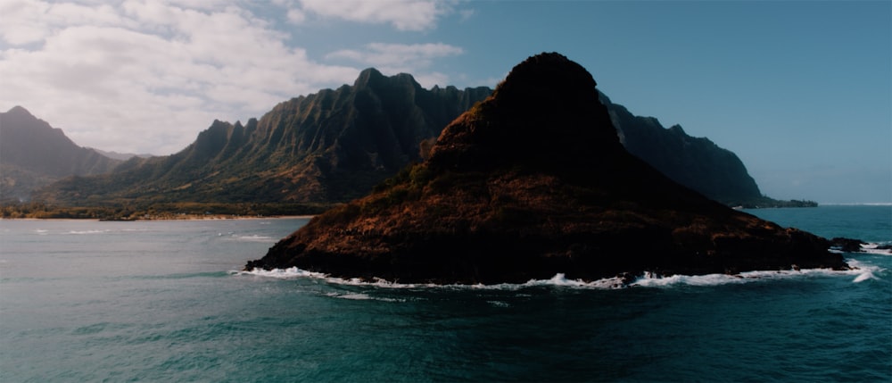 black and brown mountain surrounded by body of water