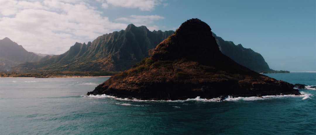 black and brown mountain surrounded by body of water