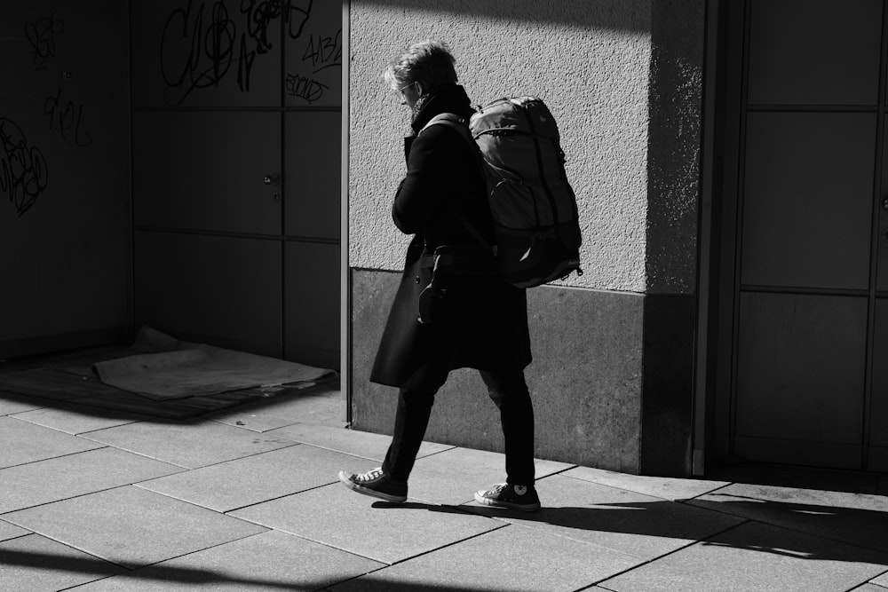 person carrying backpack beside wall