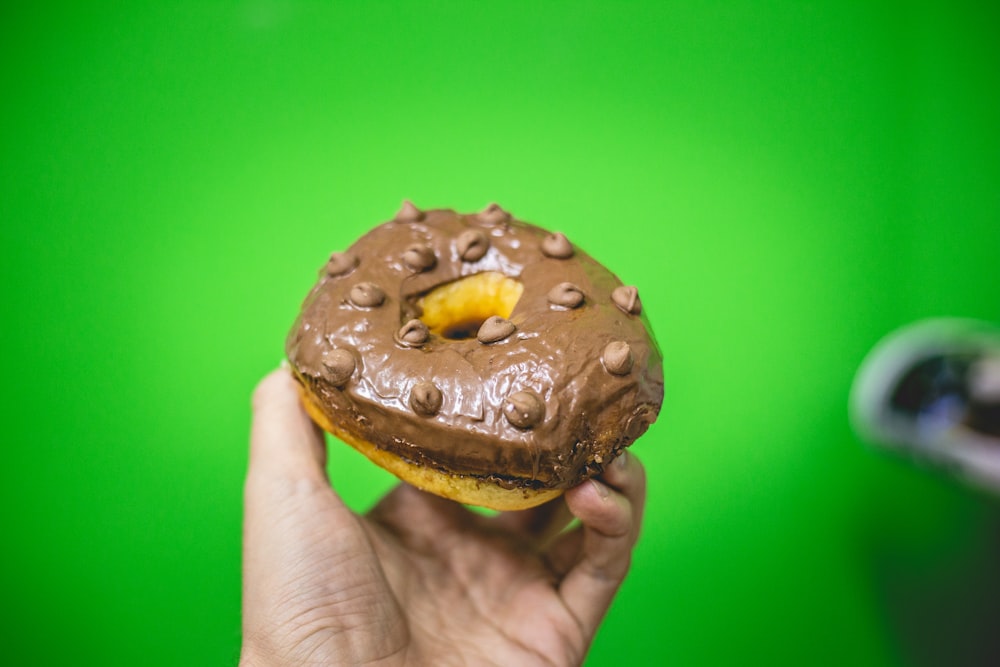 persona che tiene ciambella al cioccolato