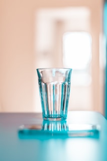 Elegant glass vessel with subtle ocean gray-blue water, placed on a muted taupe countertop.