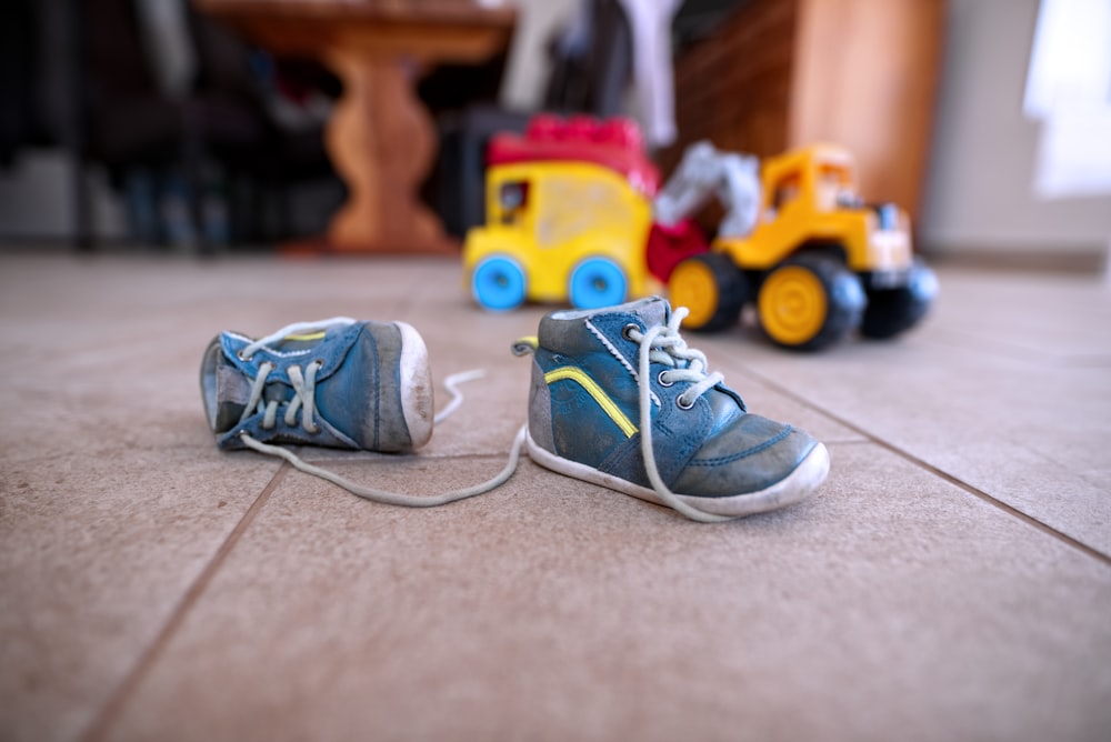 paio di scarpe da ginnastica blu vicino a giocattoli di plastica gialli