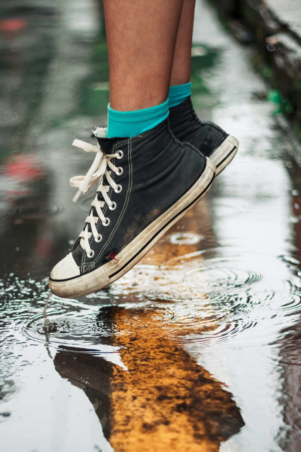 person wearing black high-top sneakers on wet floor