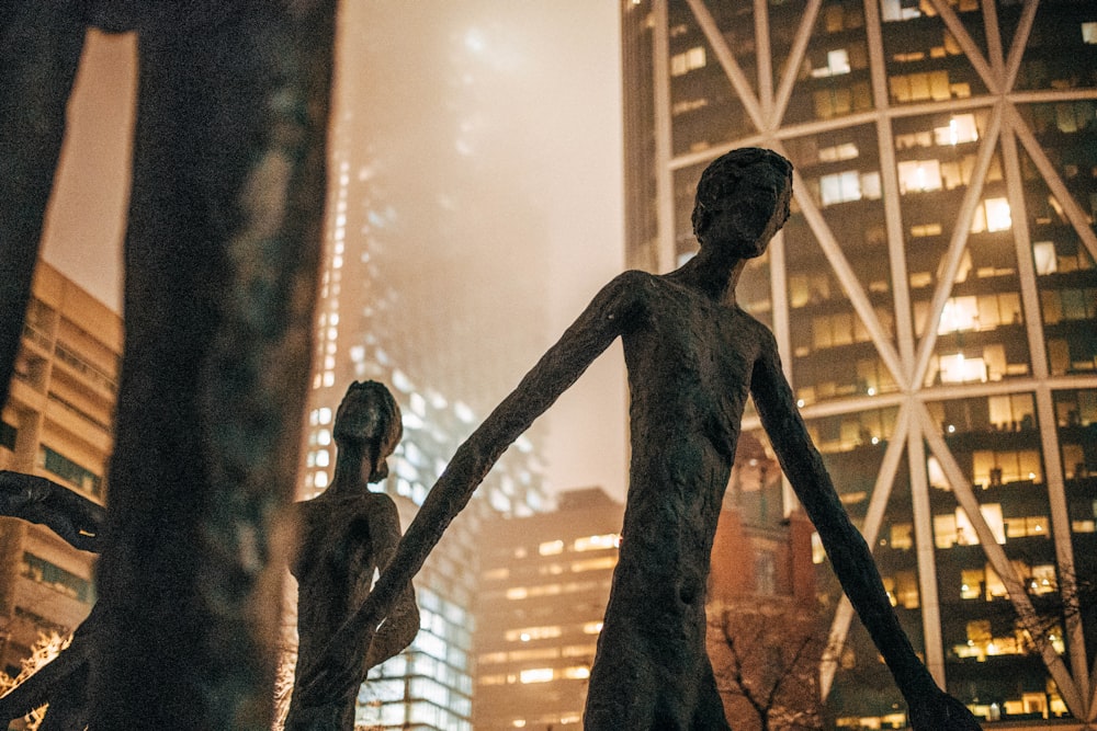 man and woman standing statue near building