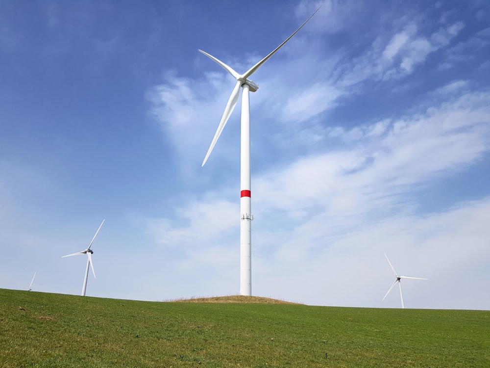 three white wind turbines on green field