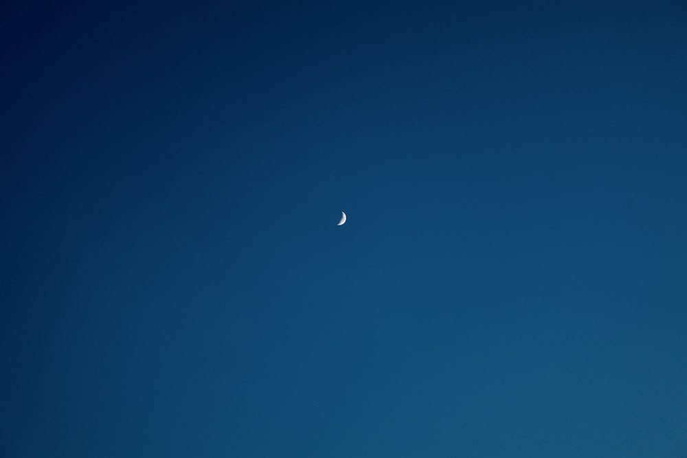 a half moon is seen in the blue sky