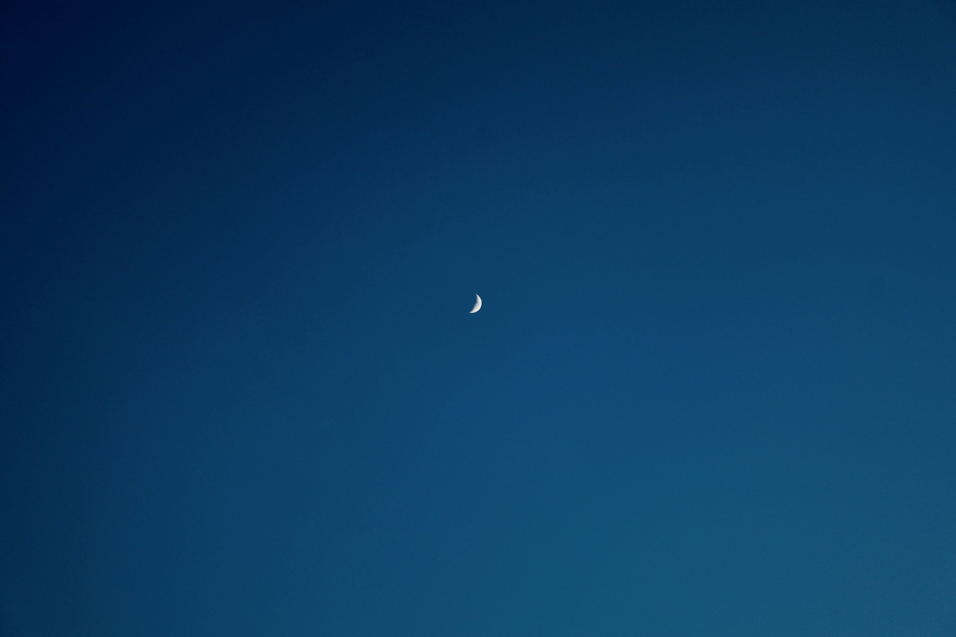 a half moon is seen in the blue sky