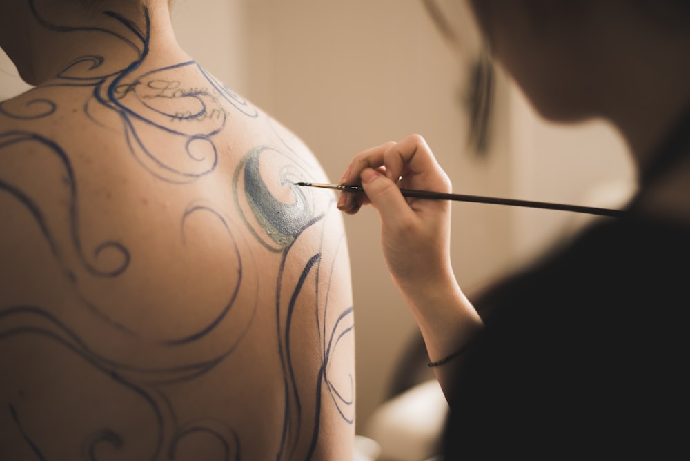 person making tattoos on the back of another person photo – Free Brown  Image on Unsplash
