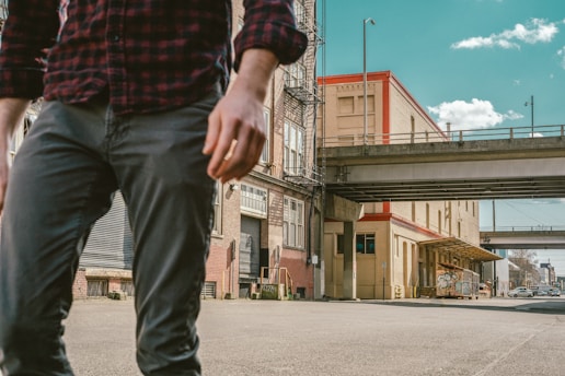 tilt-shift lens photography of gray building behind person wearing light-gray denim jeans during daytime