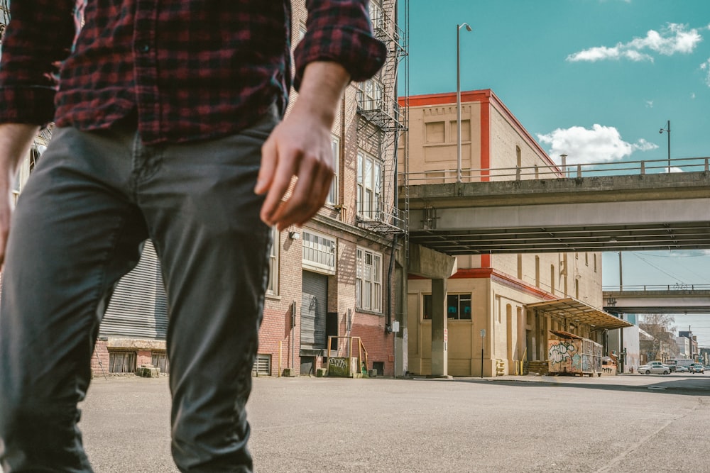 tilt-shift lens photography of gray building behind person wearing light-gray denim jeans during daytime