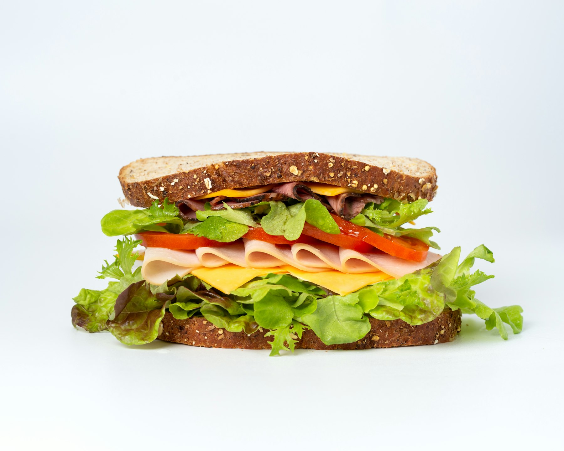 A stacked deli sandwich, photographed clean on white