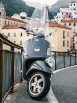 A shiny scooter parked on a cobblestone street in a sunny Italian village.