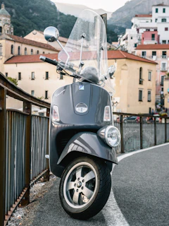 A shiny scooter parked on a cobblestone street in a sunny Italian village.