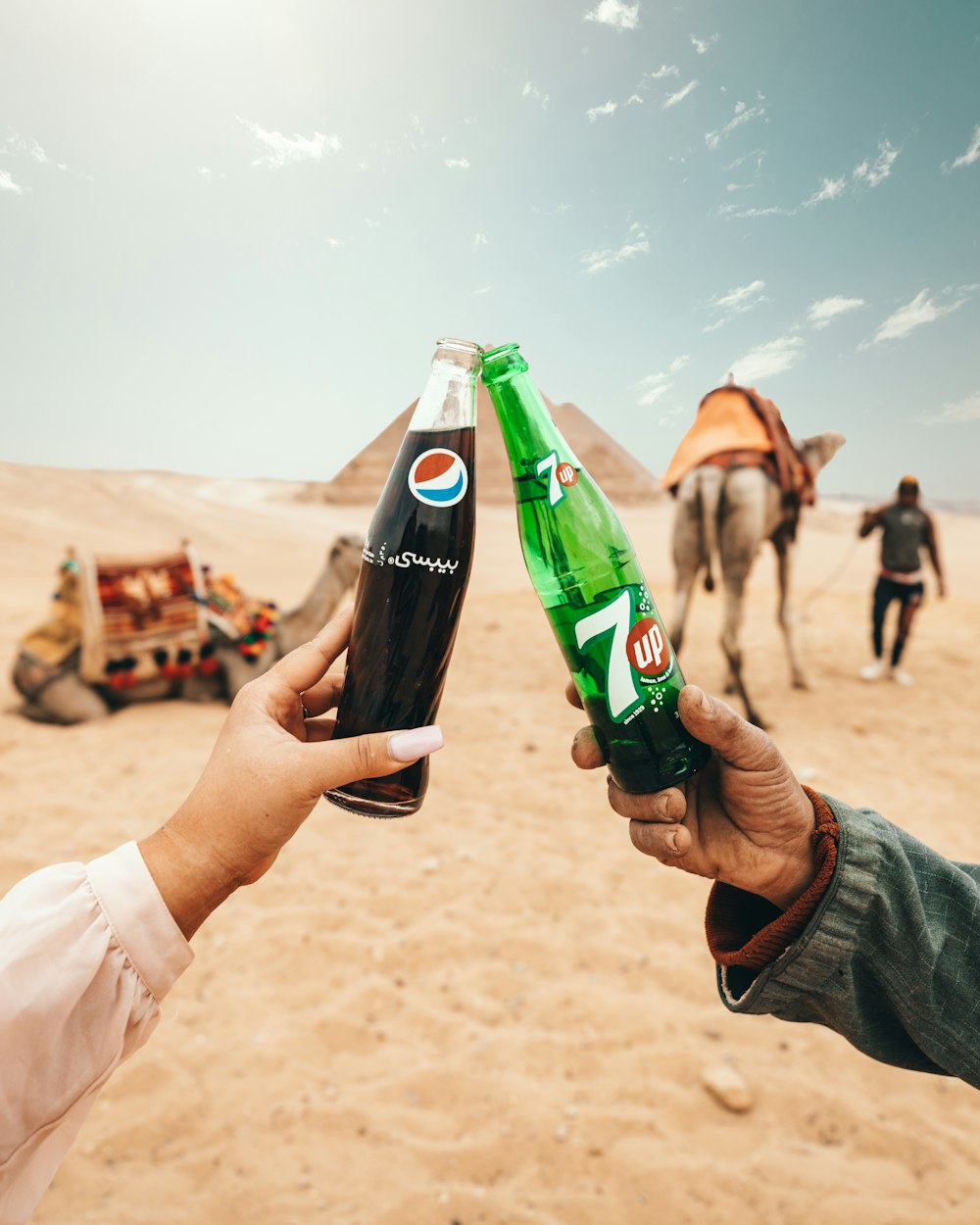 zwei Personen stoßen auf Pepsi- und 7-UP-Flaschen in Ägypten an