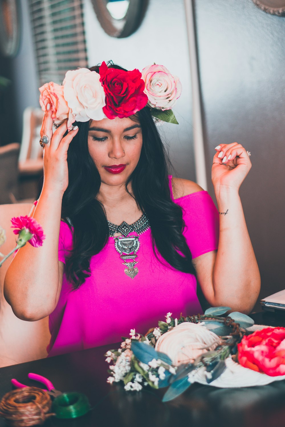 mulher que veste a coroa da flor sentada ao lado da mesa