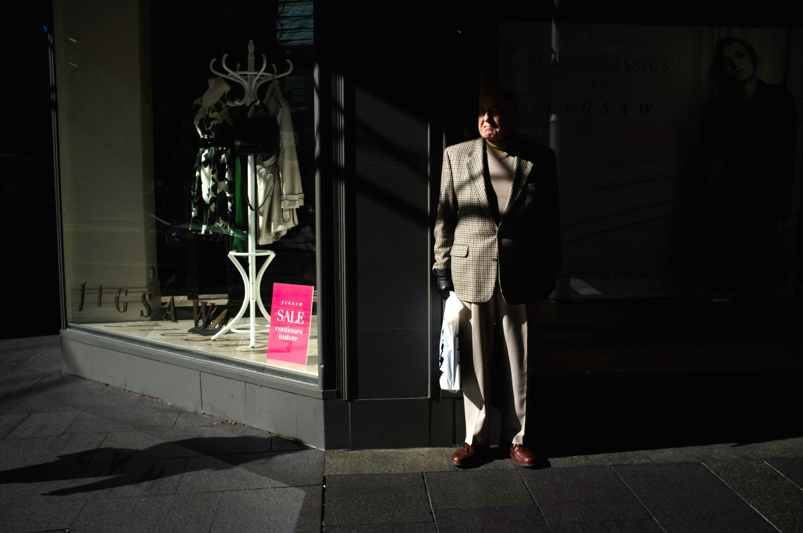 man standing beside gray wall