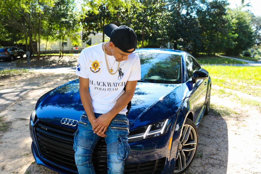 man sitting in-front of Audi coupe