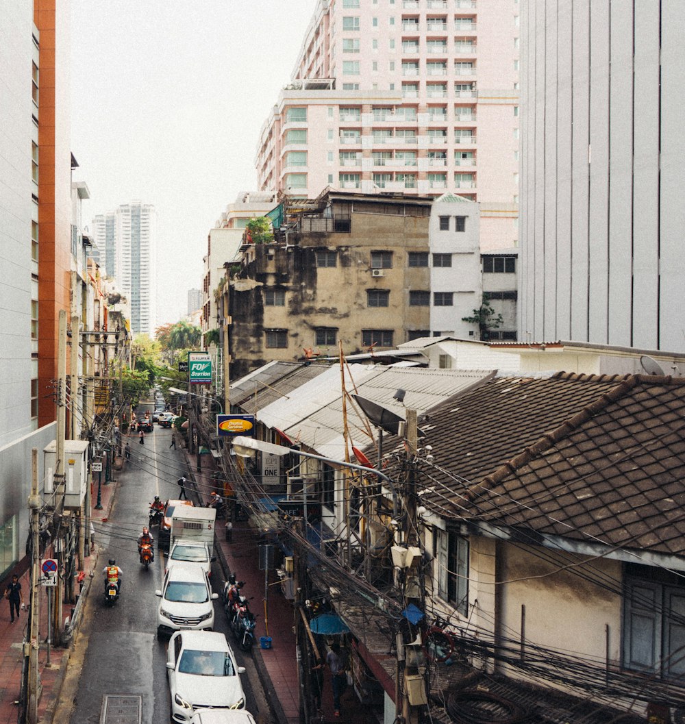 cars and motorcycles on road between buildings