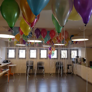 Brightly decorated party room with balloons and kids enjoying board games