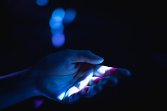 A close-up of a hand with highlighted palm lines glowing softly in blue and gold.