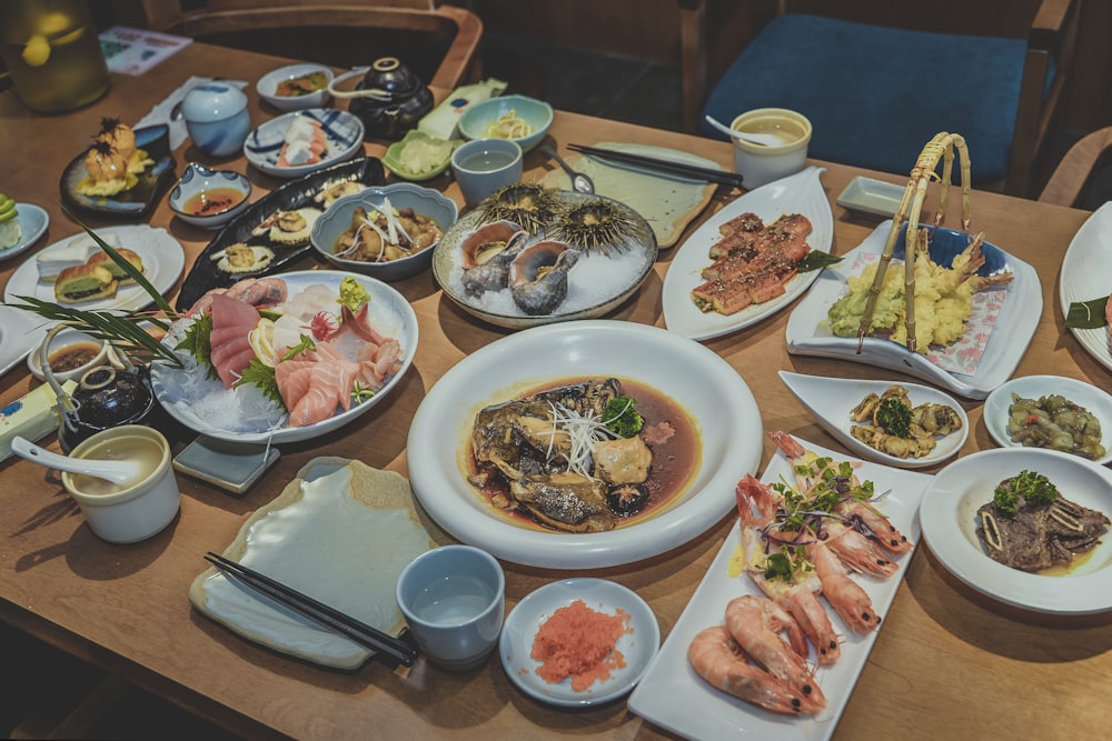 different foods in plates on brown wooden dining table