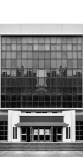 Government building entrance showcasing reflective glass doors framed by dark metal.