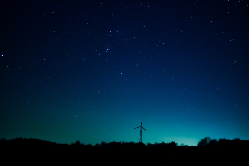 Silueta de molino de viento y árboles