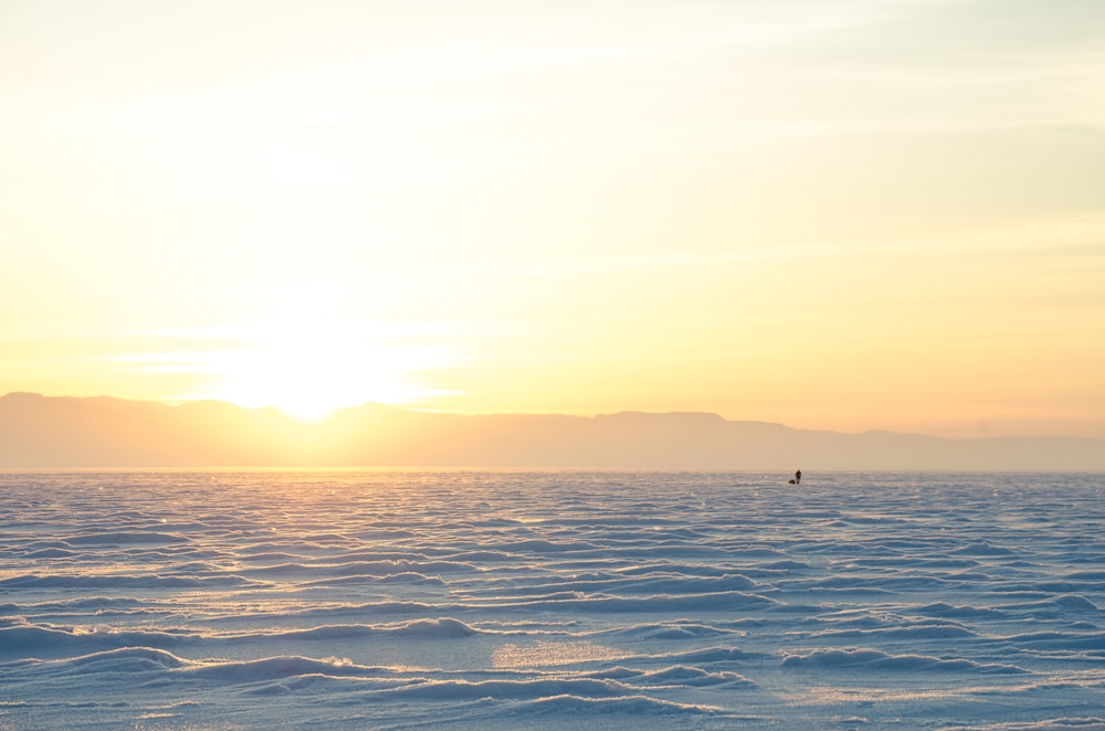 the sun is setting over the horizon of a large body of water