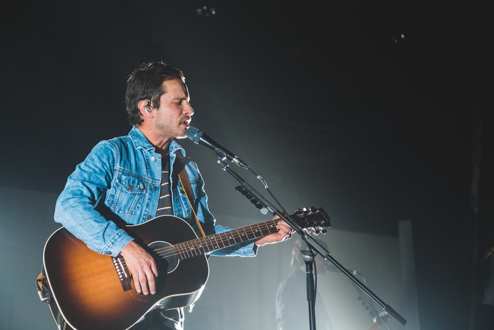 man using guitar while performing on stage