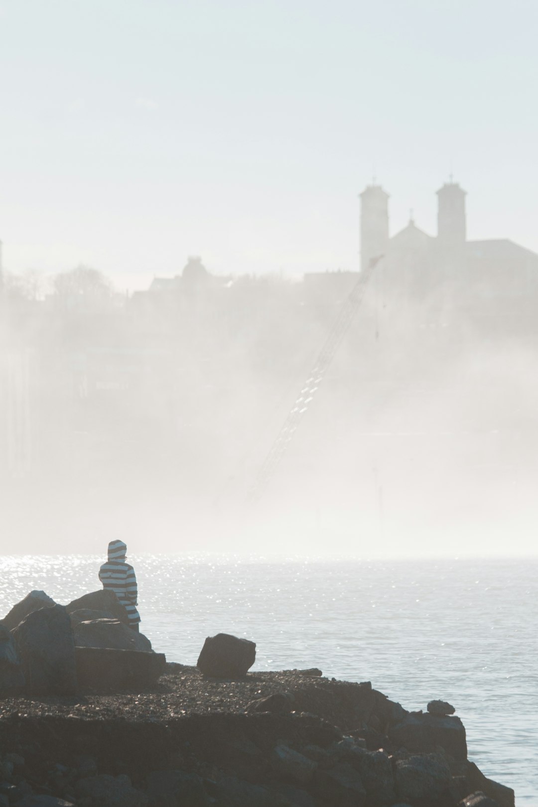 man sitting on rock near body of water