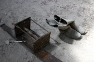 Worker's boots covered in dust next to heavy tools.