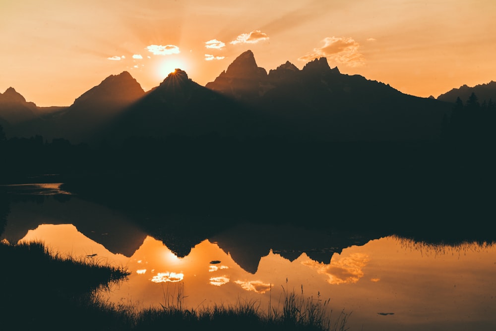 silhouette of mountain beside lake